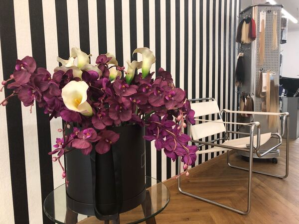 Moderner Friseursalon mit lila Orchideen, Designerstuhl und Haarverlängerungen.