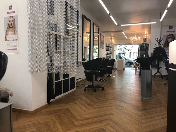 Moderner Friseursalon mit hellen Spiegeln, stylischen Stühlen und Holzfußboden.