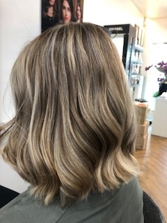 Blond balayage Bob mit sanften Wellen im modernen Friseursalon von hinten fotografiert.